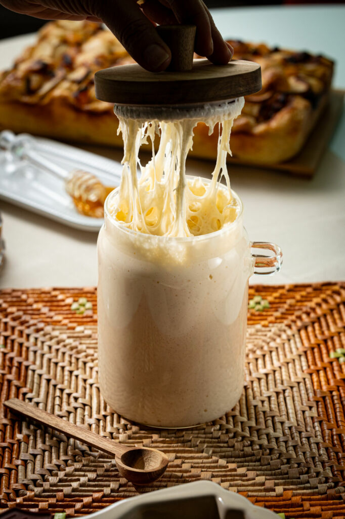 Fermento natural sendo puxado de um pote de vidro, usado no preparo de cucas alemãs artesanais.